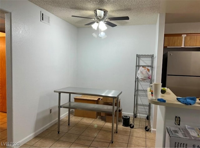 tiled dining room with a textured ceiling and ceiling fan