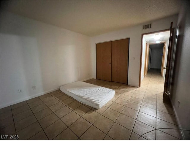 unfurnished bedroom with light tile patterned floors and a closet