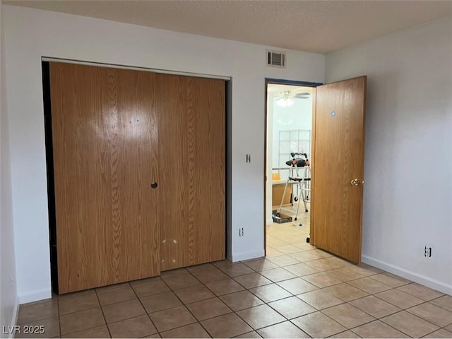 unfurnished bedroom with a textured ceiling, a closet, and light tile patterned flooring