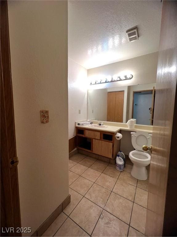 bathroom with tile patterned floors, vanity, a textured ceiling, and toilet