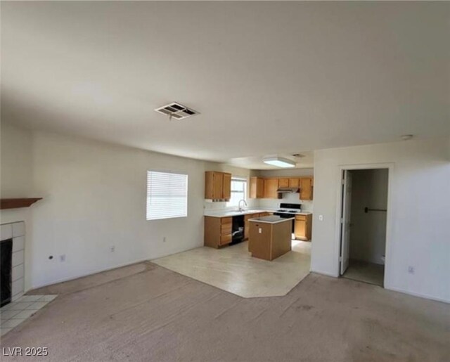 kitchen with a kitchen island, sink, a fireplace, and light carpet