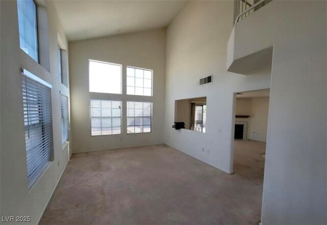 unfurnished living room with light carpet and high vaulted ceiling