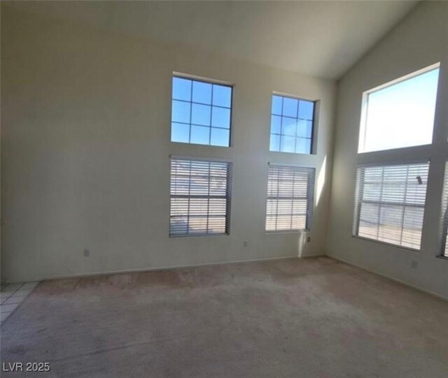 carpeted empty room with high vaulted ceiling