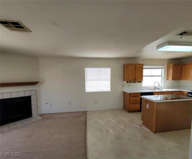 kitchen featuring a fireplace, a center island, light colored carpet, and sink