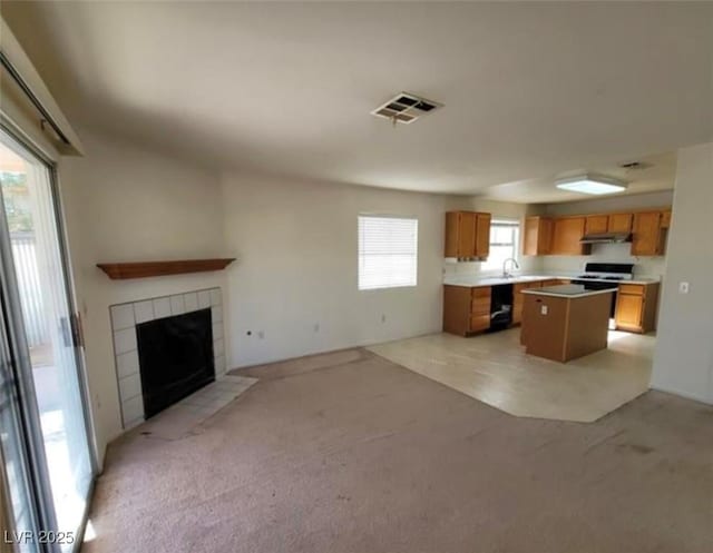 kitchen with light carpet, a kitchen island, plenty of natural light, and a fireplace