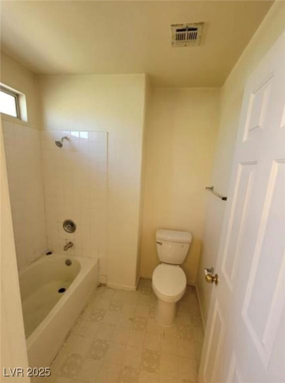 bathroom featuring tiled shower / bath combo and toilet