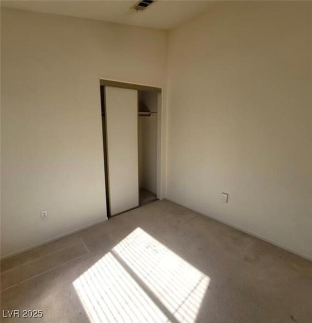 unfurnished bedroom with a closet and light colored carpet