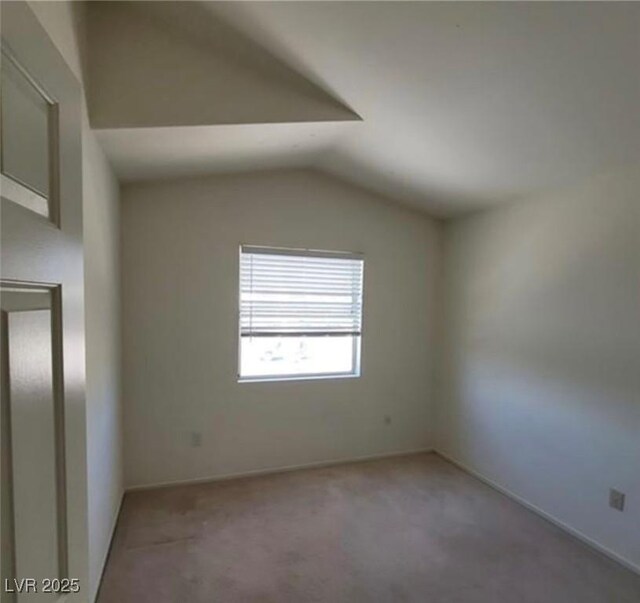 empty room with light colored carpet and vaulted ceiling