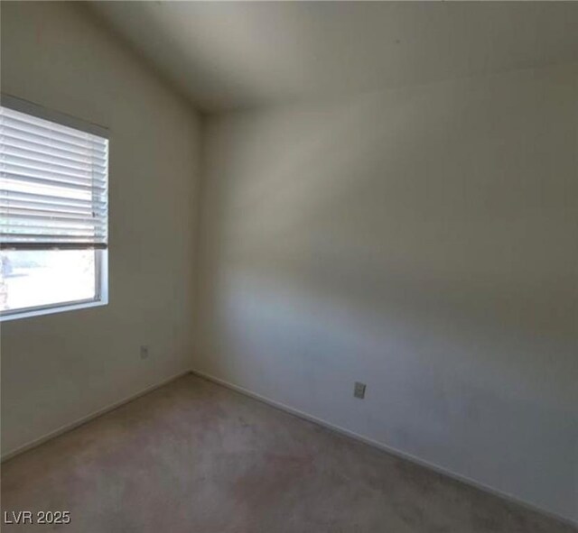 spare room with carpet floors and vaulted ceiling