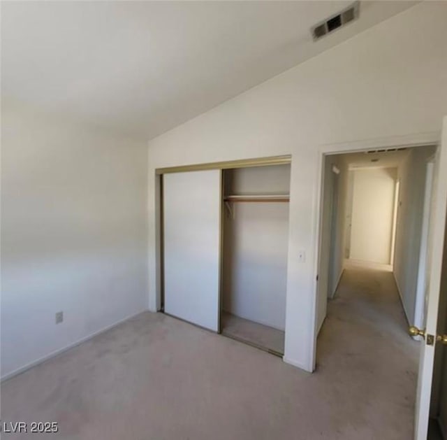 unfurnished bedroom with light colored carpet, a closet, and lofted ceiling