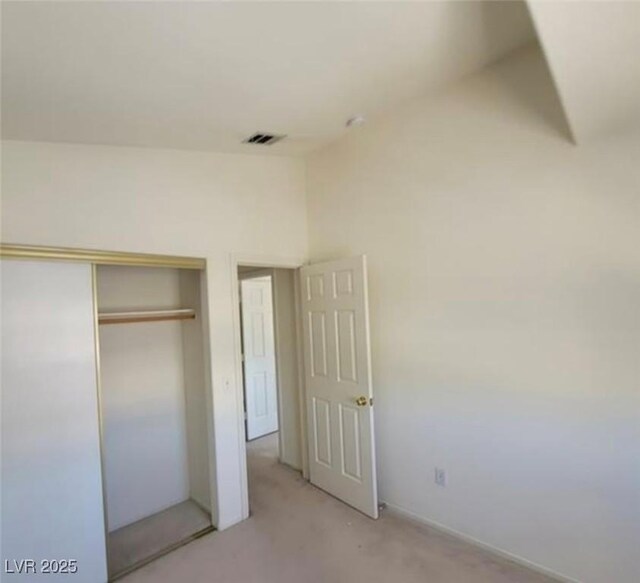 unfurnished bedroom featuring light colored carpet and a closet