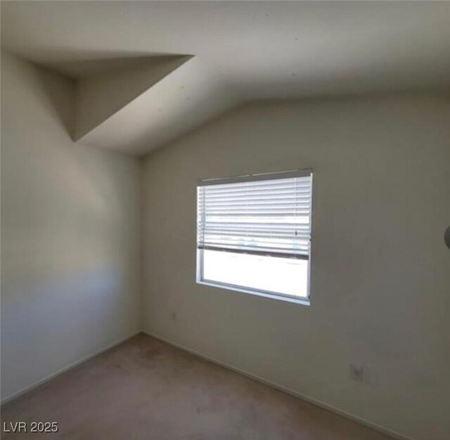 empty room featuring carpet floors and vaulted ceiling