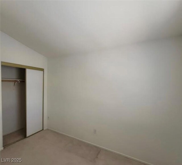 unfurnished bedroom featuring a closet, light colored carpet, and vaulted ceiling