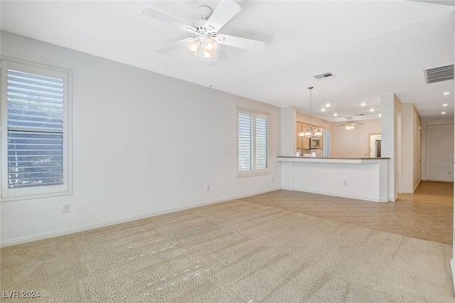 unfurnished living room with light carpet and ceiling fan with notable chandelier