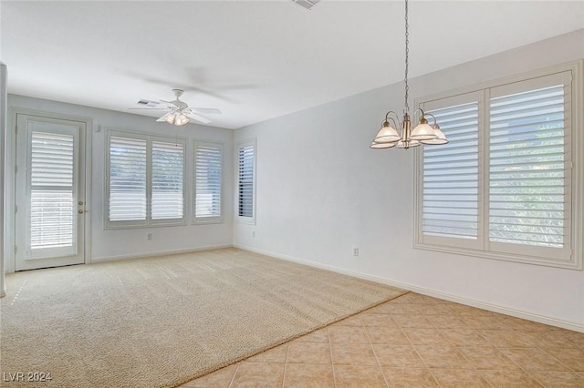 tiled spare room with ceiling fan with notable chandelier