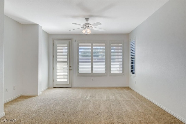 empty room featuring a wealth of natural light, ceiling fan, and light carpet