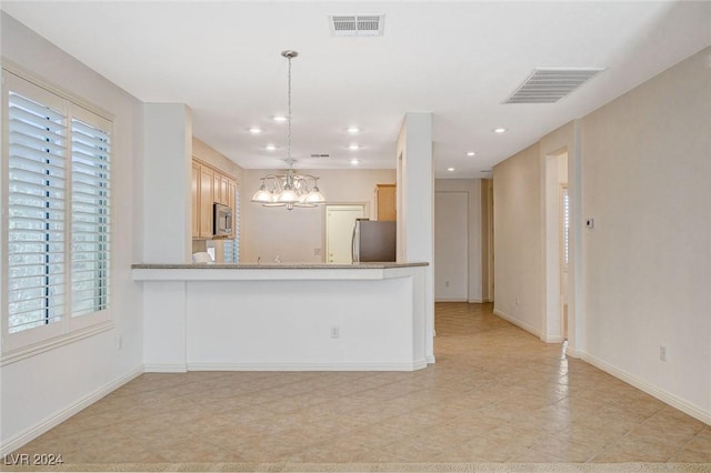 kitchen featuring hanging light fixtures, light brown cabinetry, appliances with stainless steel finishes, kitchen peninsula, and a chandelier