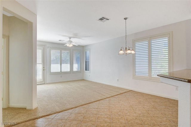 unfurnished dining area featuring light tile patterned floors and ceiling fan with notable chandelier