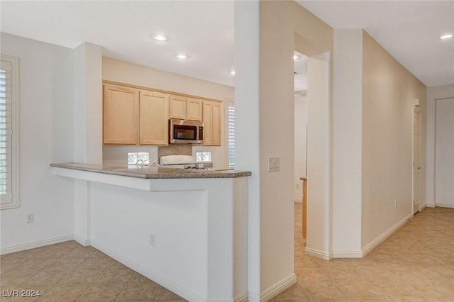 kitchen with stove, light brown cabinets, tasteful backsplash, and light tile patterned flooring