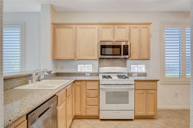 kitchen with sink, light brown cabinets, plenty of natural light, light tile patterned floors, and appliances with stainless steel finishes