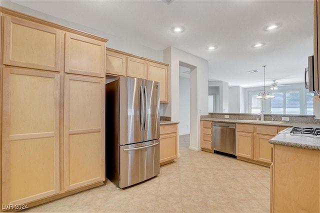 kitchen with appliances with stainless steel finishes, sink, light brown cabinets, decorative light fixtures, and a notable chandelier