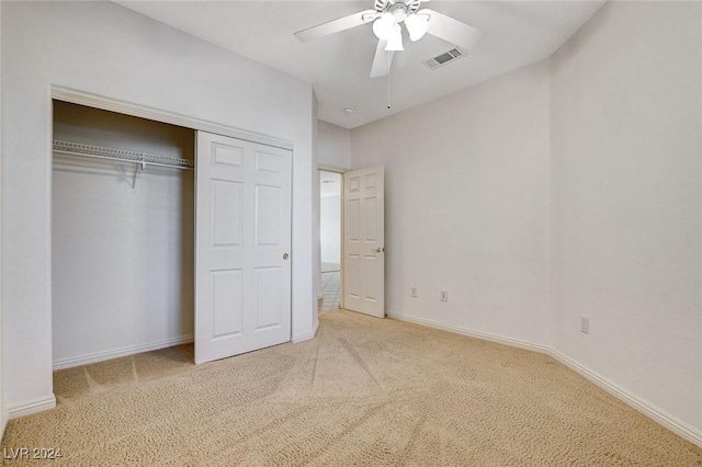 unfurnished bedroom with ceiling fan, light colored carpet, and a closet