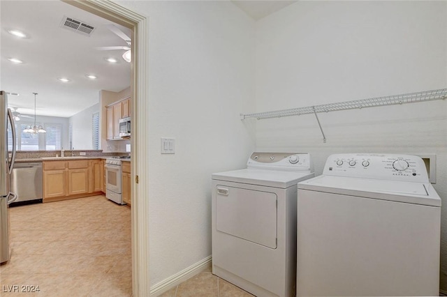 laundry area with ceiling fan with notable chandelier, separate washer and dryer, sink, and light tile patterned floors