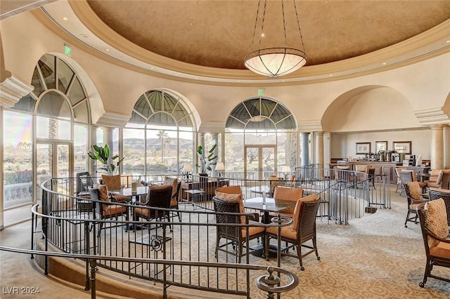 dining room featuring carpet, a towering ceiling, a raised ceiling, and ornate columns