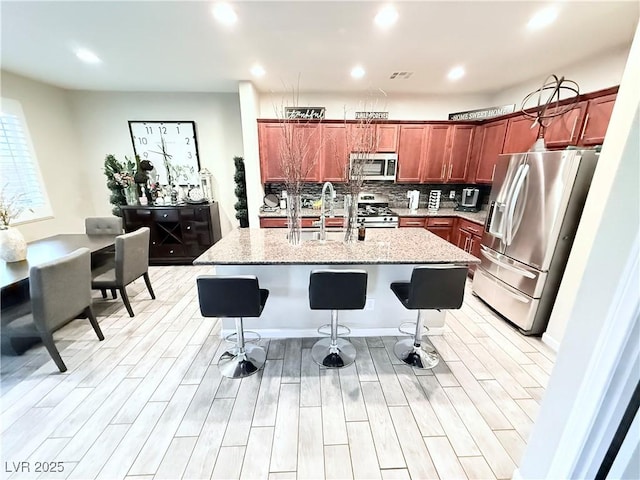 kitchen with appliances with stainless steel finishes, sink, a kitchen breakfast bar, and a kitchen island with sink