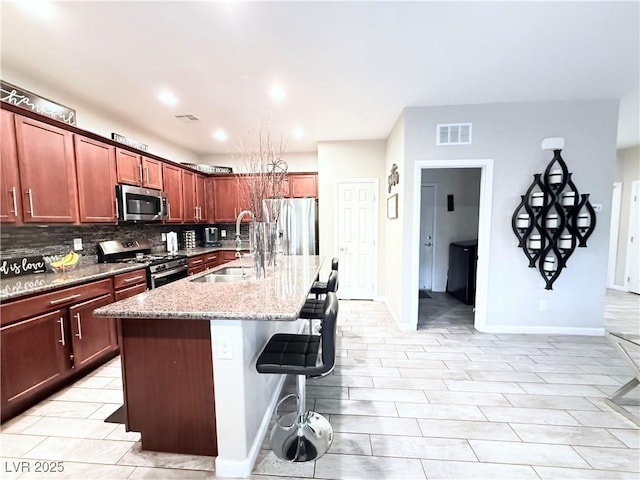 kitchen featuring a center island with sink, tasteful backsplash, stainless steel appliances, a breakfast bar, and sink