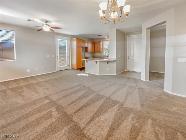 unfurnished living room featuring ceiling fan with notable chandelier and light carpet