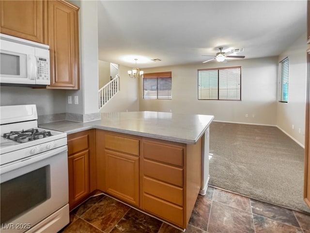 kitchen featuring kitchen peninsula, ceiling fan with notable chandelier, white appliances, and dark colored carpet