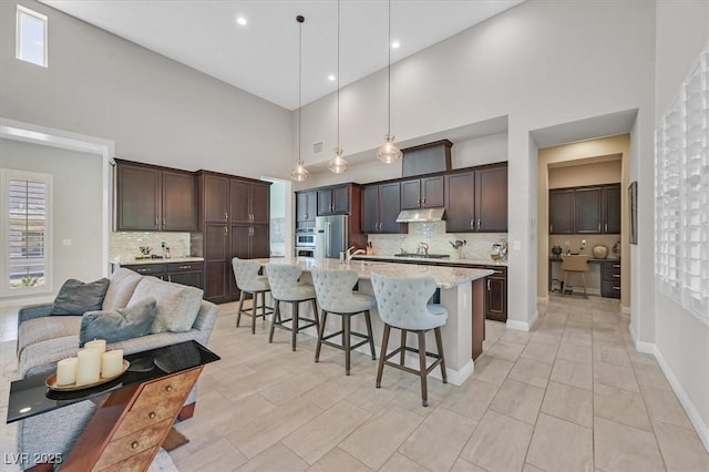 kitchen with backsplash, a kitchen bar, hanging light fixtures, and a high ceiling