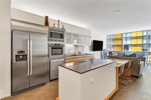 kitchen with white cabinetry, sink, a center island, and built in appliances