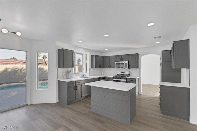 kitchen featuring sink, a center island, stainless steel appliances, tasteful backsplash, and gray cabinets