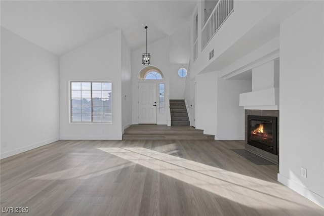 entrance foyer with a tile fireplace, hardwood / wood-style flooring, and high vaulted ceiling