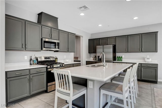 kitchen with a kitchen bar, gray cabinetry, sink, and stainless steel appliances