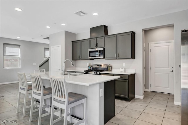 kitchen featuring gray cabinetry, sink, a kitchen breakfast bar, a center island with sink, and appliances with stainless steel finishes