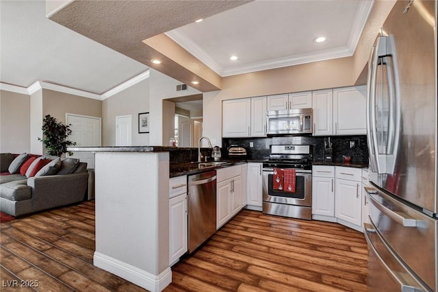 kitchen featuring kitchen peninsula, decorative backsplash, white cabinets, and stainless steel appliances