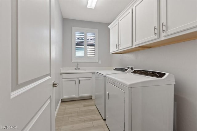 clothes washing area with washing machine and clothes dryer, sink, cabinets, and light hardwood / wood-style flooring