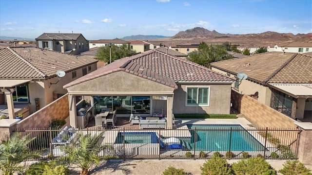 back of house with a fenced in pool, a mountain view, a patio, and an outdoor hangout area