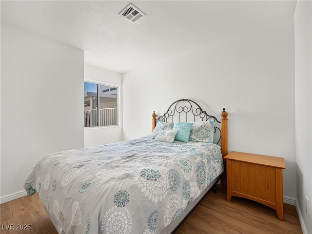 bedroom featuring hardwood / wood-style flooring and a textured ceiling