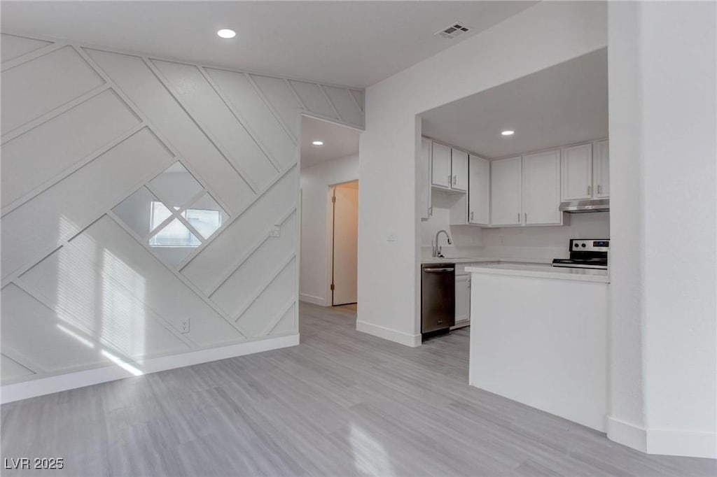 kitchen featuring appliances with stainless steel finishes, light hardwood / wood-style floors, white cabinetry, and sink