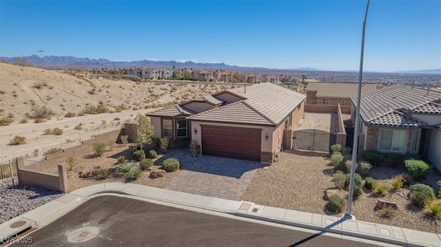 view of front facade with a garage, a tile roof, fence, decorative driveway, and stucco siding