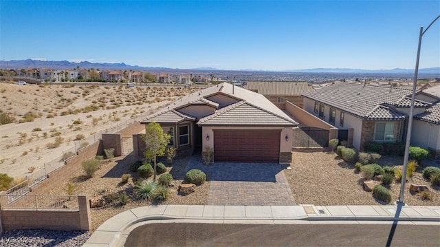 ranch-style house with decorative driveway, stucco siding, a mountain view, a garage, and a tiled roof