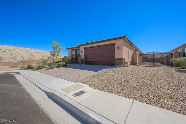 view of front of house with an attached garage, fence, decorative driveway, and stucco siding