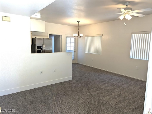 unfurnished room featuring dark colored carpet and ceiling fan with notable chandelier