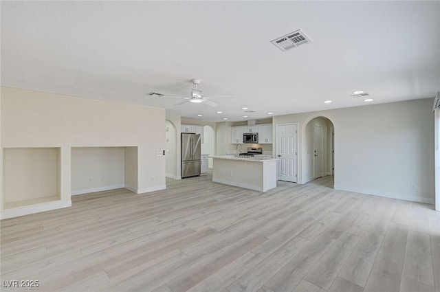 unfurnished living room with light hardwood / wood-style floors, ceiling fan, and sink