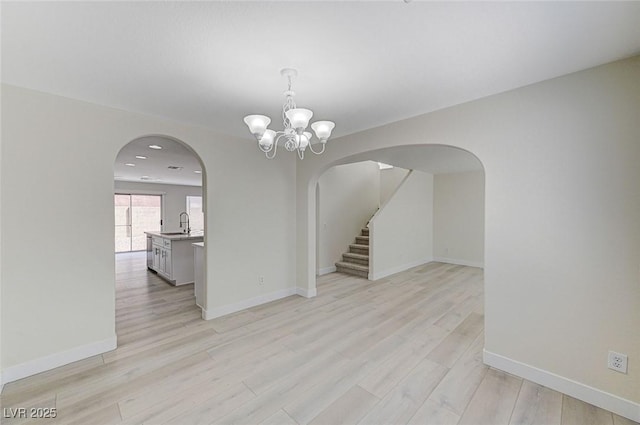 spare room featuring a notable chandelier, sink, and light hardwood / wood-style flooring