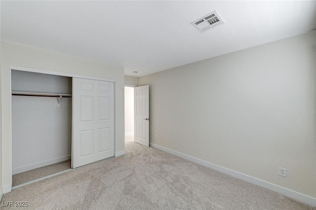 unfurnished bedroom with light carpet and a closet